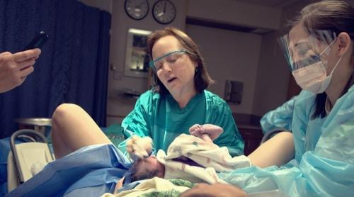 O obstetriciană, pe punctul de a naște, face o pauză pentru a-și ajuta pacienta să aducă pe lume un bebeluș! 